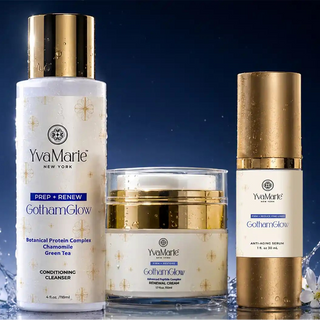 Three YanMarie New York skincare products arranged together on a reflective blue surface against a dark blue background with light effects: a tall white bottle with a gold cap, a white jar with a gold lid, and a tall white bottle with a gold cap.