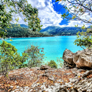 Turquoise lake surrounded by mountains and trees on a sunny day